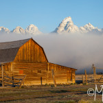 Barn at sunrise as clouds reveal the Grand Tetons; WY