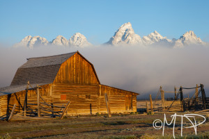 Barn at sunrise as clouds reveal the Grand Tetons; WY